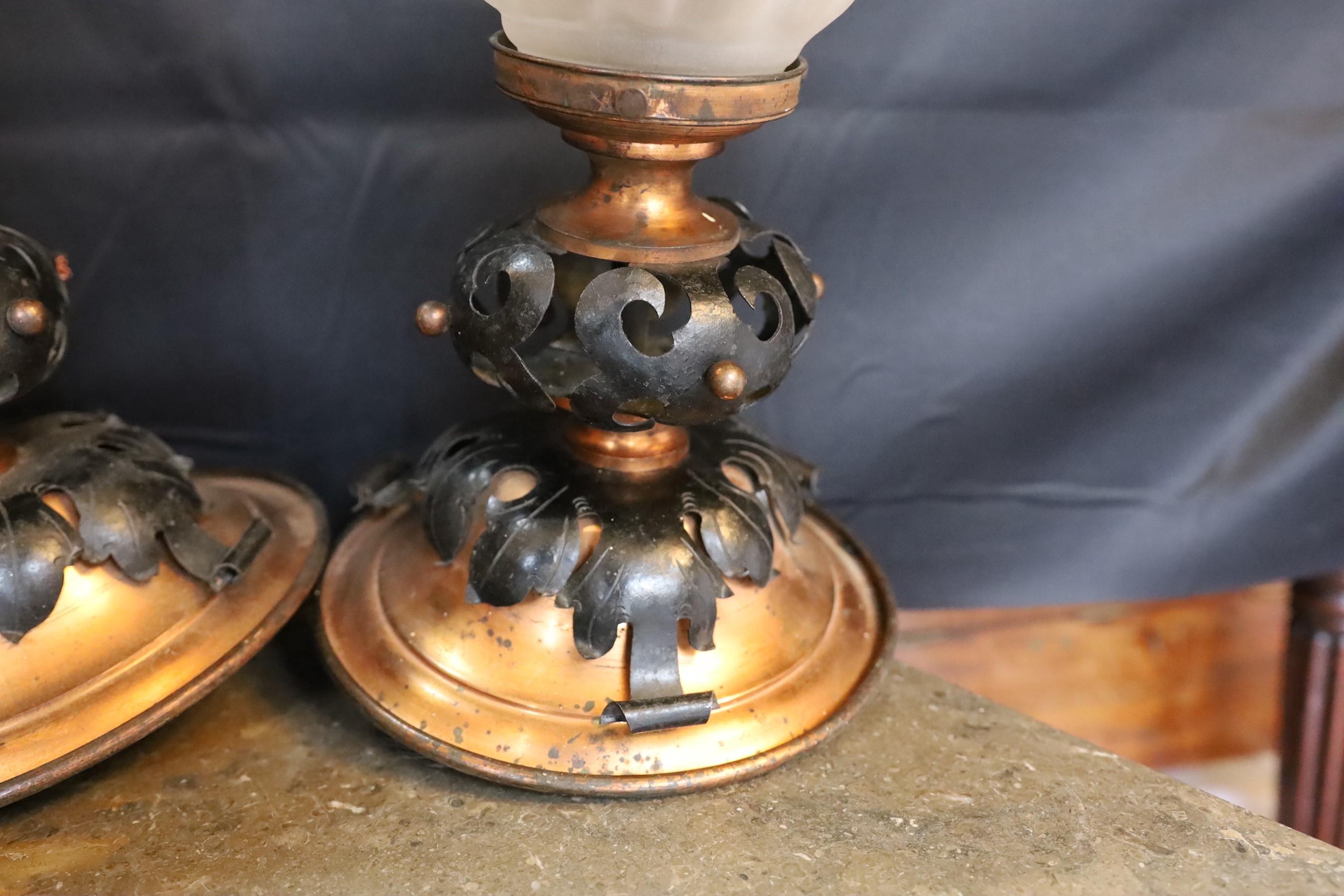 A pair of French Arts & Crafts copper and wrought iron ceiling lights with flambeau frosted glass shades, height 37cm. width 21cm
